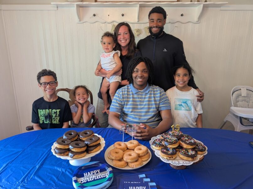 Cameron and family gathered around a table of donuts for a 15th birthday