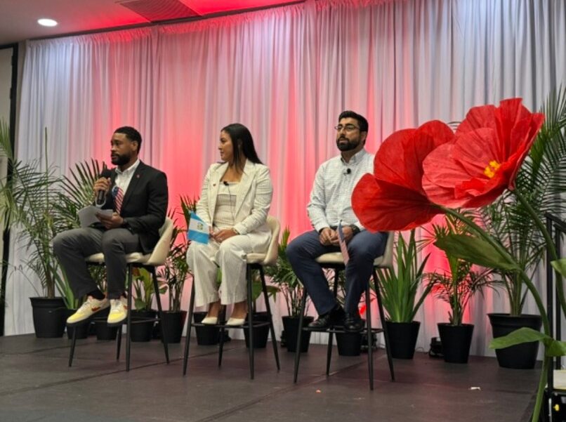 Cameron holding a microphone while moderating a panel on stage